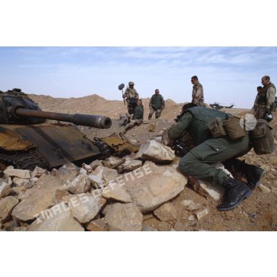 Une équipe de tournage et un photographe de l'ECPA (Etablissement cinématographique et photographique des Armées) ont pour sujet un char de combat T-55 irakien détruit.