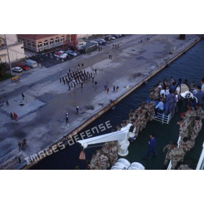 Des soldats accoudés au bastingage suivent la manoeuvre d'accostage du ferry affrété Danielle Casanova le long du quai dans la rade de Toulon.