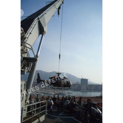 Un hélicoptère de combat Gazelle du 3e RHC (régiment d'hélicoptères de combat) est treuillé par une grue du TCD (transport de chalands de débarquement) Foudre vers le quai du port de Toulon.