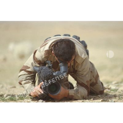 Un brigadier caméraman de l'ECPA (Etablissement cinématographique et photographique des Armées) filme à terre en direction de l'objectif.