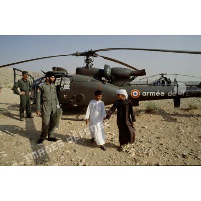 Pilotes français et émiratis avec des enfants émiratis, devant un hélicoptère de combat Gazelle de l'ALAT (aviation légère de l'armée de terre).