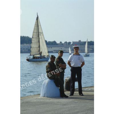 Attente avant l'embarquement sur le ferry affrété Girolata, sur le bord du quai pour un marin et deux légionnaires.