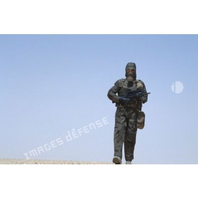 Soldat armé d'un fusil d'assaut FAMAS en tenue complète S-3P (survêtement de protection à port permanent) pour un entraînement NBC.