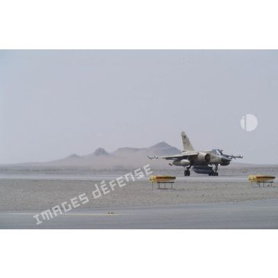 Un avion de combat Mirage F1-CRde l'ER (escadron de reconnaissance) 2/33 Savoie (cocotte), armé de missiles Matra R-550 Magic II en bout d'ailes, s'avance sur la piste de la BA (base aérienne) d'Al Ahsa.