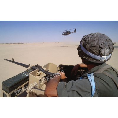 Surveillance du désert depuis la tourelle d'un VAB. A l'arrière-plan, un hélicoptère de combat Gazelle en survol.