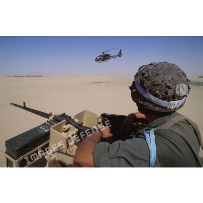 Surveillance du désert depuis la tourelle d'un VAB. A l'arrière-plan, un hélicoptère de combat Gazelle en survol.