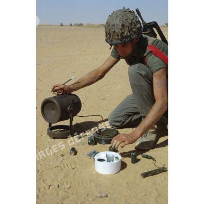 Un soldat du génie manipule une mine de type MI AC AH F1 (mine antichar à action horizontale).