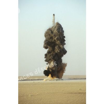 Explosion dans le désert. Une colonne de fumée noire s'élève dans le ciel lors d'un entraînement au tir à l'explosif.