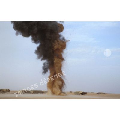 Explosion dans le désert. Une colonne de fumée noire s'élève dans le ciel lors d'un entraînement au tir à l'explosif.