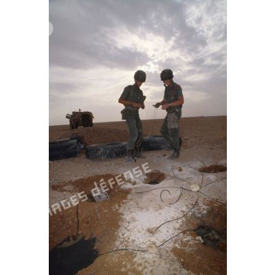 Des soldats du génie enfouissent des pains de plastic dans le sable et posent des mèches lentes pour préparer un fourneau d'explosion lors d'un entraînement au tir à l'explosif.