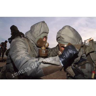 Un soldat en tenue S-3P (survêtement de protection à port permanent) et portant l'ANP (appareil normal de protection) ôte le masque de son camarade lors de l'exercice NBC du 1er RI.