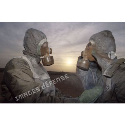 Deux soldats en tenue S-3P (survêtement de protection à port permanent) et portant l'ANP (appareil normal de protection) se décontaminent grâce au gant de décontamination chimique d'urgence lors de l'exercice NBC du 1er RI.