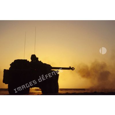 Tir d'un blindé de reconnaissance AMX-10 RC sur le pas de tir en contre-jour au coucher du soleil.