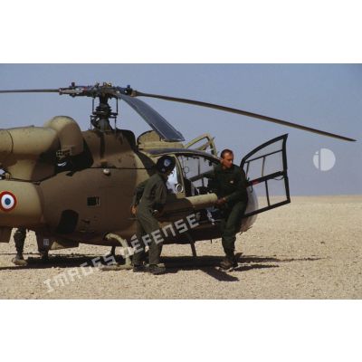 Deux personnels de l'ALAT (aviation légère de l'armée de terre) approvisionnent un hélicoptère de combat Gazelle SA-342 en missiles HOT.