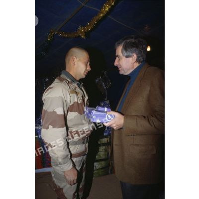 Jean-Pierre Chevènement, ministre de la Défense, remet un cadeau de Noël à un légionnaire du 2e REI.