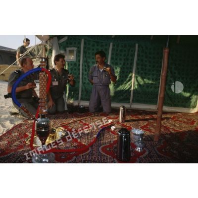 Sous une tente saoudienne, des aviateurs français de la BA (base aérienne) d'Al Ahsa et des membres de l'équipe de l'ECPA (Etablissement cinématographique et photographique des Armées) boivent le thé offert par les bédouins.