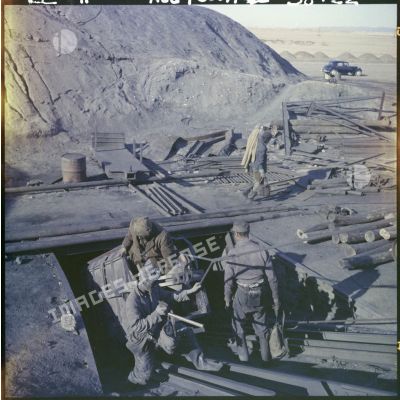 Un groupe d'hommes à l'entrée d'une mine souterraine.