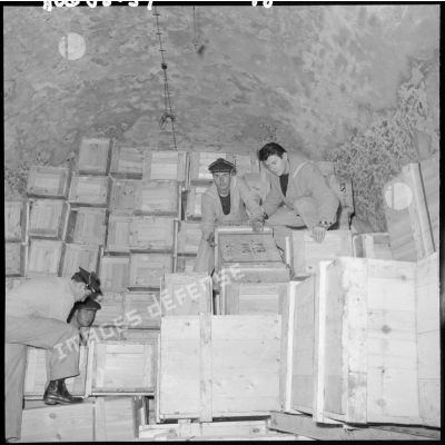 Des marins entassant des caisses dans un entrepôt.