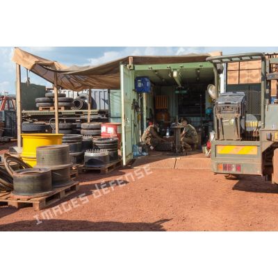 Des mécaniciens effectuent une réparation sur la roue d'un véhicule, à l'atelier de réparation mécanique du train de combat du camp de M'Poko de Bangui.