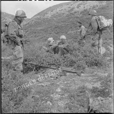Un parachutiste garde une mitrailleuse MG 42 ainsi que deux prisonniers.