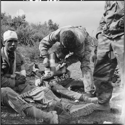 Un parachutiste infirmier soigne quelques rebelles blessés.