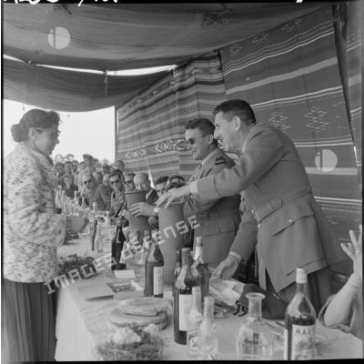 A la table du banquet, le général Jacques Massu et une autorité s'entretiennent avec une femme.