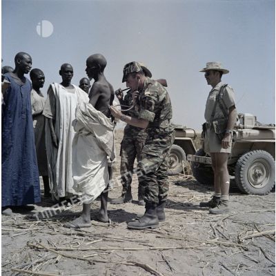 Un capitaine médecin français ausculte un paysan tchadien malade.
