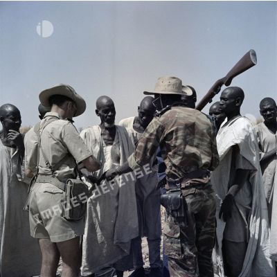 Un capitaine français et un gendarme tchadien discutent avec les hommes d'un village.