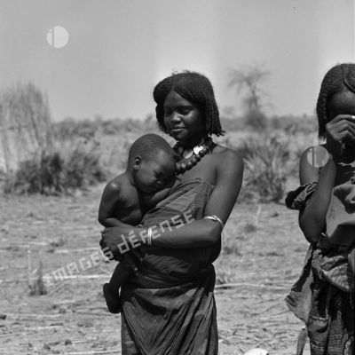 Portrait d'une jeune femme tchadienne qui porte un bébé dans ses bras.