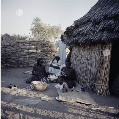 Deux femmes et deux hommes devant une case au Tchad.
