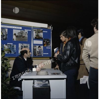 Un homme accueille des étudiants sur un espace du stand de l'exposition Jeunesse 1976, dans l'ancienne gare de la Bastille à Paris.