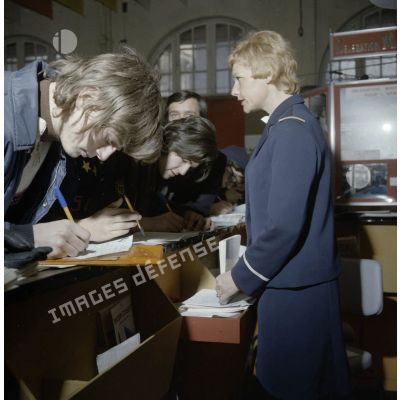 Une hôtesse accueille des étudiants sur un espace de l'exposition Jeunesse 1976, dans l'ancienne gare de la Bastille à Paris.