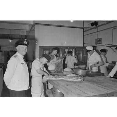 Un vétérinaire de la Kriegsmarine dans une cuisine où des marins préparent de la viande.