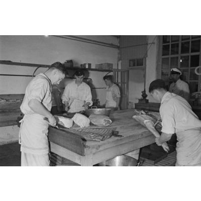 Marins allemands de la Kriegsmarine préparent des carcasses de porc dans une cuisine.