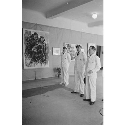 Guidés par les reporters Heinrich Schwich et  Lothar-Günther Buchheim (pas visible), les Kapitänleutnant Jost Metzler et Herbert Kuppisch visitent une exposition de dessins et de peintures à l'hôtel Royal de La Baule.