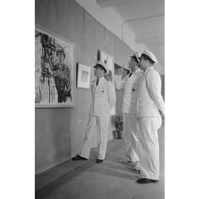 Guidé par les reporters Heinrich Schwich et Lothar-Günther Buchheim, le Kapitänleutnant  Herbert Kuppisch visite une exposition de dessins et de peintures à l'hôtel Royal de La Baule.