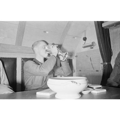 A la table réservée aux officiers du bord, un officier du sous-main U-boot U-203 boit un liquide contenu dans un Ehrenpokal.