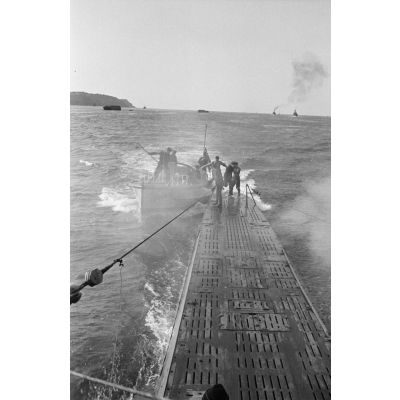 Peu avant le retour de croisière au port de Brest, un bateau se rapproche du U-boot U-203 pour y faire monter des marins.
