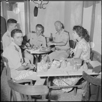 Des officiers déjeunent avec une jeune femme dans un restaurant.