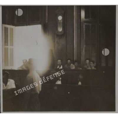 Un homme debout à l'intérieur de la salle du palais de justice où sont jugés les criminels de guerre japonais.