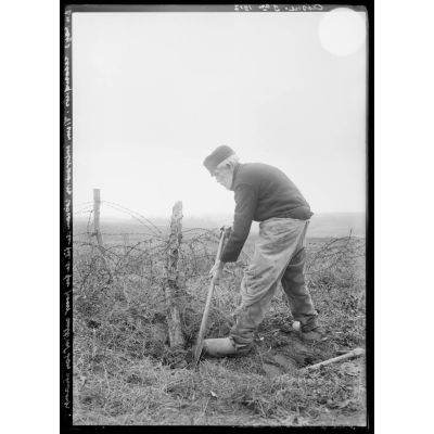 En pays reconquis, Vieux enlevant un réseau de fil de fer pour cultiver son champ, Aisne, novembre 1917. [légende d'origine]