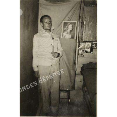 [Portrait de l'appelé du contingent Raymond Le Gall tenant une quille dans une chambrée en Algérie, 1958.]