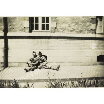 [Photographie de groupe de soldats assis par terre au pied d'un bâtiment en Algérie, 1954-1962.]