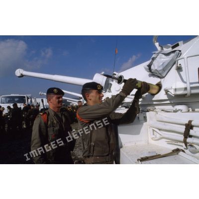 Capitaine observant un marsouin du 1er régiment d'infanterie de marine (1er Rima) chargeant un obus 90 mm dans un véhicule blindé à roues ERC-90 Sagaie aux couleurs de l'ONU.