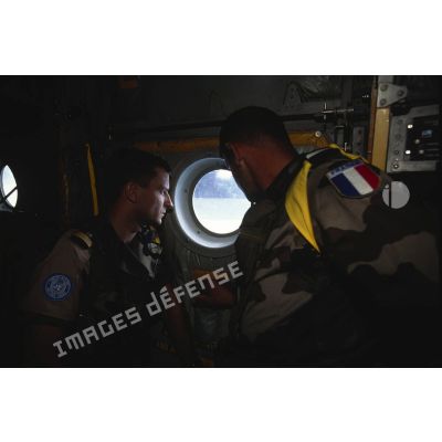 Un capitaine et un adjudant du 14e régiment parachutiste de commandement et de service (14e RPCS) regarde par le hublot d'un avion Hercules C-130.