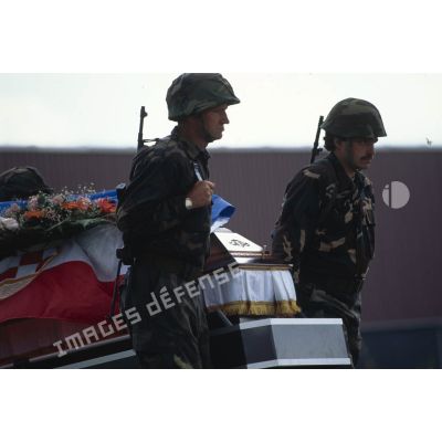 Deux militaires croates de Bosnie entourent un cercueil couvert d'un drapeau croate lors d'une levée de corps à Trogir, sur le camp ONU du détachement de l'aviation légère de l'Armée de terre (DETALAT).