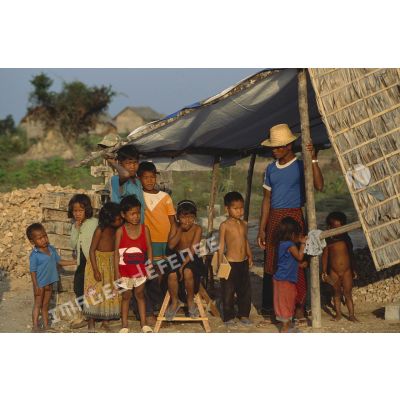 Groupe d'enfants avec un adulte devant une habitation en construction dans un village de réfugiés près de Siem Reap.