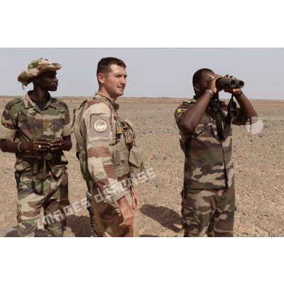 Un soldat malien observe une zone de tir au moyen de jumelles Vector 21 sous la supervision d'un artilleur du 93e régiment d'artillerie de montagne (RAM) à Tessalit, au Mali.
