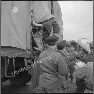 Femme de harki partant pour la France aidée par les soldats du 26e régiment d'infanterie motorisé (RIM).