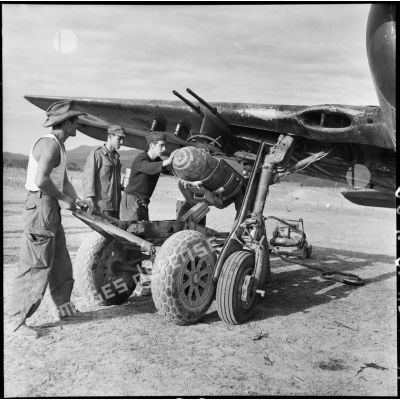 Installation d'une bombe sous l'aile d'un avion Curtiss SB2C Helldiver sur le terrain d'aviation de Diên Biên Phu.